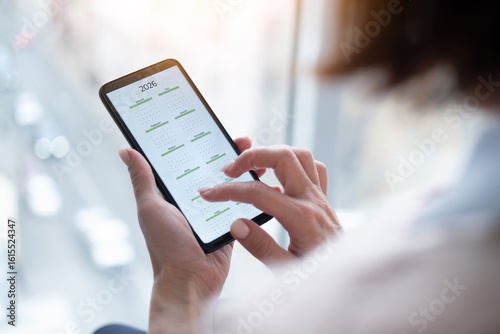 Wallpaper Mural Close-Up Of A Woman Holding A Smartphone Displaying The 2026 Calendar Torontodigital.ca