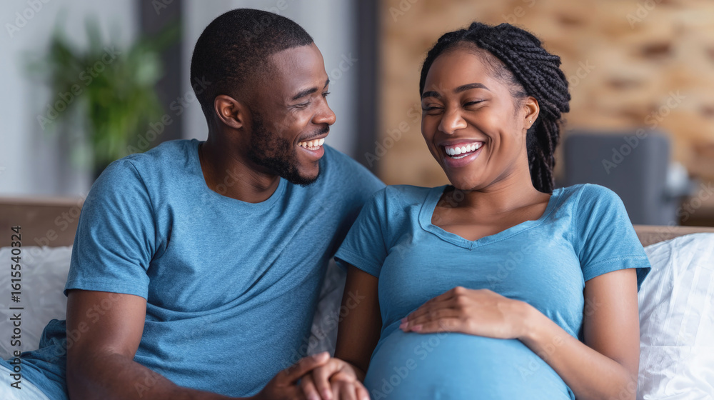 Fototapeta premium Happy expecting couple sitting on couch, smiling and enjoying bonding moment together during pregnancy at home.