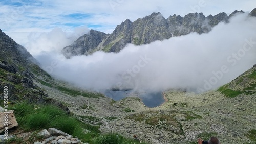 View over a mountain lake shrouded in mist, beneath the Rysy peak in the Tatra Mountains.