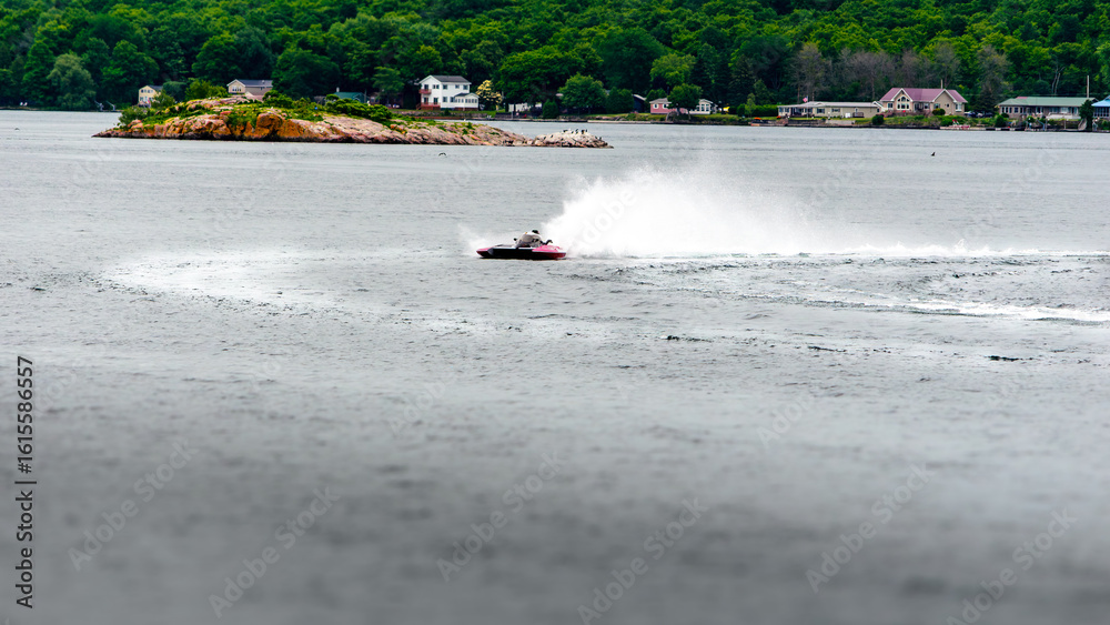 Obraz premium Single red and white hydroplane boat throwing spray on the water