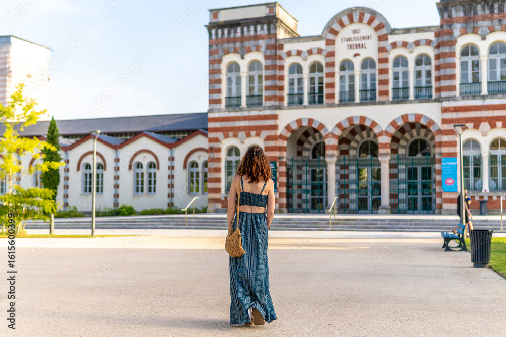Naklejka premium Tourist walking towards thermal baths in salies de bearn, france