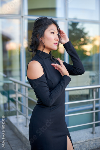Free Download A lady in a black outfit is standing outside the house. She's wearing elegant stilettos. The tight-fitting dress highlights her graceful curves. - GFXLoad