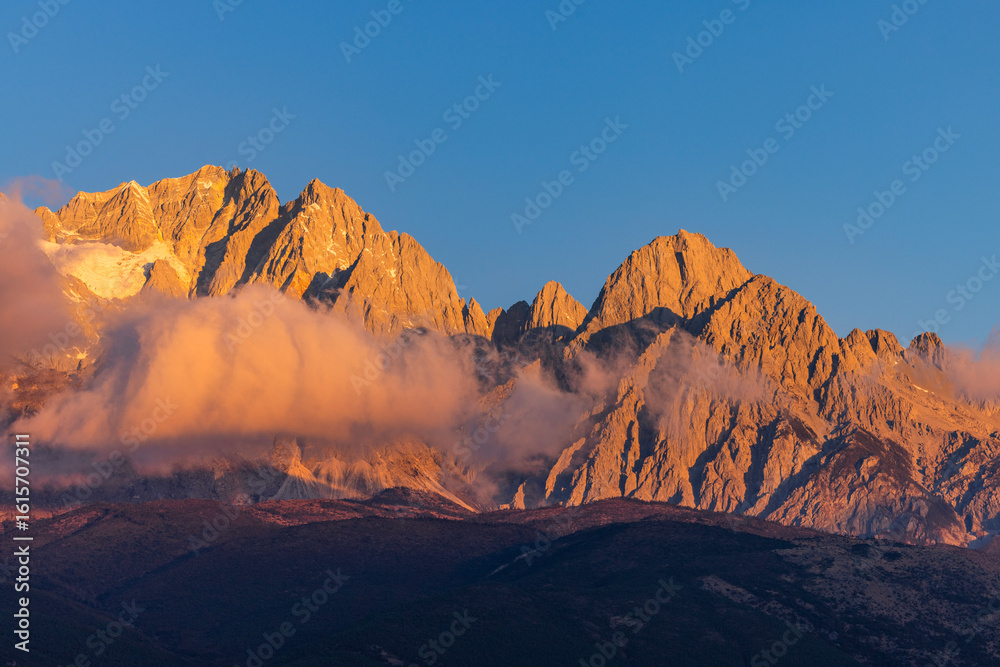 Naklejka premium The view of Yulong Snow Mountain bathed in sunlight on the golden Mountain