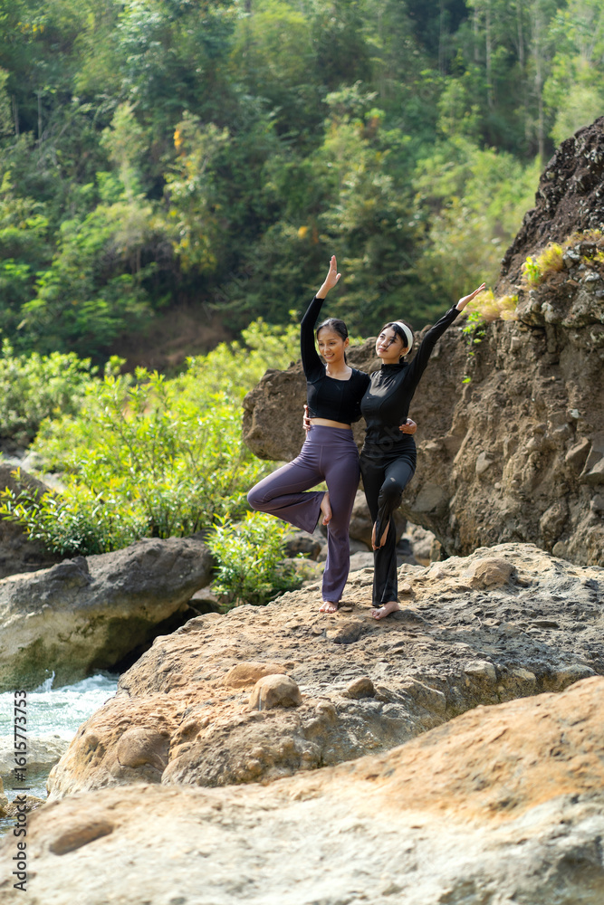 Obraz premium Asian Indonesian Women Doing Yoga Exercise in Nature on Rocky Riverside