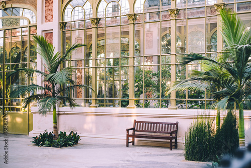 Photography Lush tropical interior of Hivernacle glasshouse with bench and palm trees in Bar