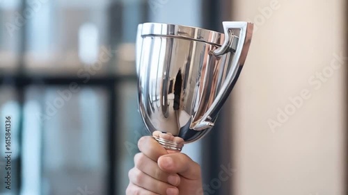 Confident businessman triumphantly holding trophy celebrates success in modern office environment