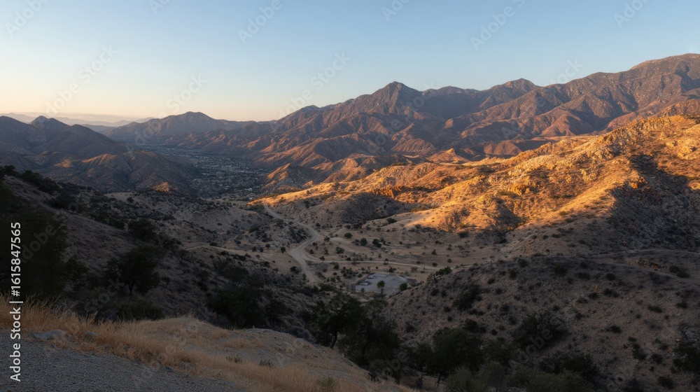 Fototapeta premium Panoramic view of rugged mountain terrain at sunrise or sunset, warm light accentuating contours,