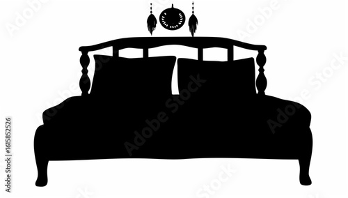 Silhouette of a bed with pillows and a dreamcatcher hanging above the headboard in black and white