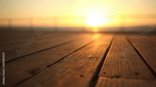 Close up of weathered wooden planks on a pier leading to a glowing sunrise or sunset over calm water,