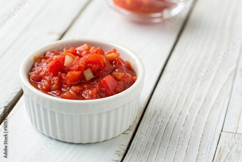 Freshly chopped tomato salsa in a white ramekin dish isolated on white background