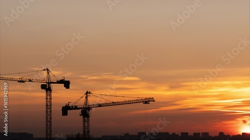 Working cranes silhouettes on the beautiful sunset background at hot summer night. Time lapse