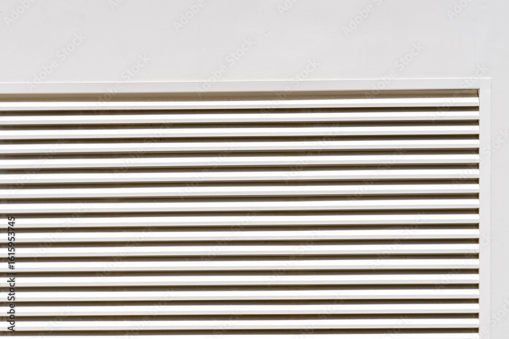 Obraz premium Zoom sur des grilles d’aération de couleur crème, intégrées discrètement dans une façade ou un mur clair.