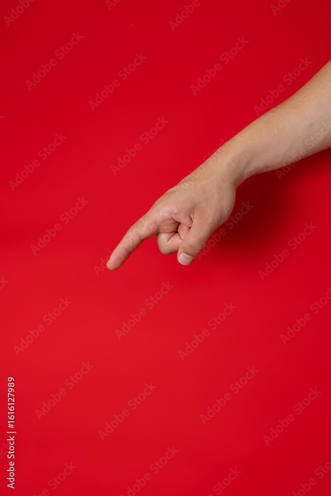 Fototapeta Male hand pointing finger at a red background for advertising text, concept of p