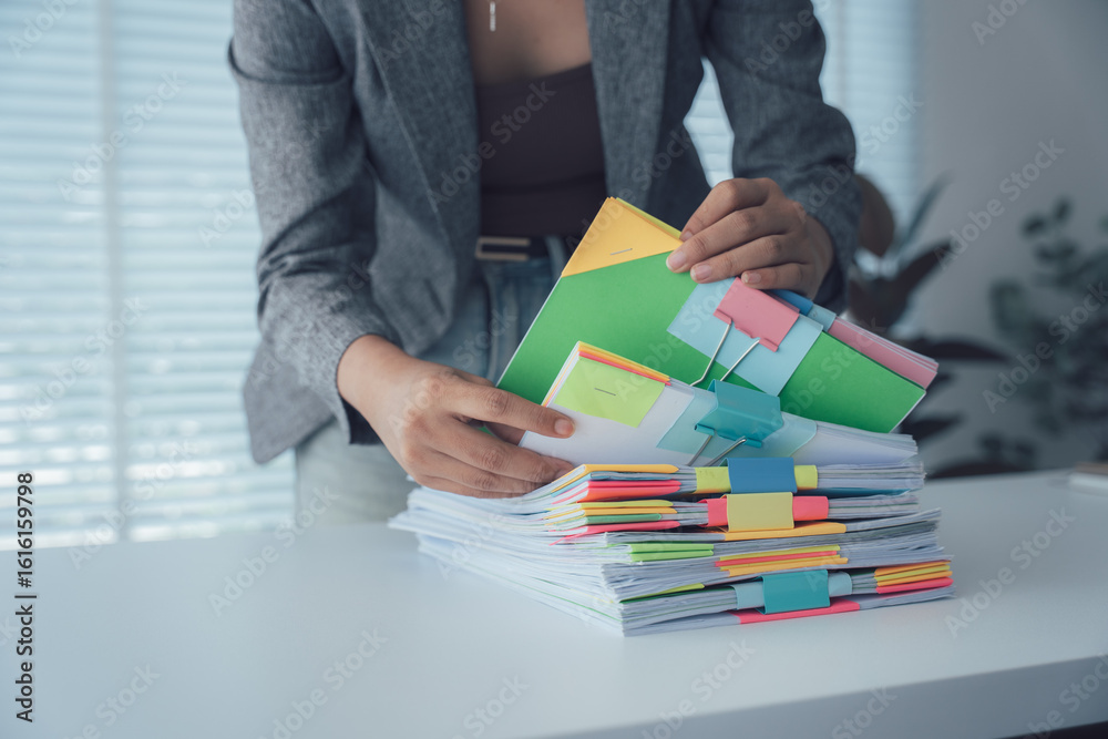 Φωτογραφία Organized Documents: A focused individual meticulously arranges and examines a collection of organized documents, showcasing professionalism and attention to detail in a well-lit office environment