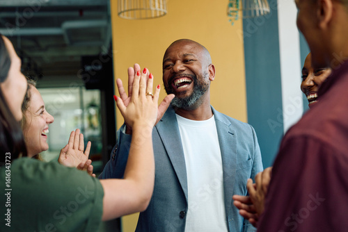Successful business people celebrating with high five gesture in office during daytime
