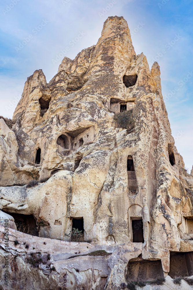 Fototapeta premium Hand carved rooms in unusual rock formation in Goreme, Cappadocia, Turkey Old houses constructed inside many caves inside mountains created by lava flows. 