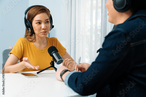 Εκτύπωση καμβά Smiling radio influencer host wearing headphone interviewing woman speaker sharing information to listeners on social media online website live streaming channel at morning at studio record