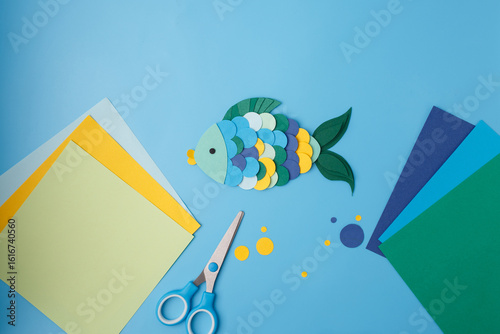 Handmade paper fish with glue and scissors on colorful background for education publishers, kids creative workshops, art magazines, craft blogs, and toy design presentations.