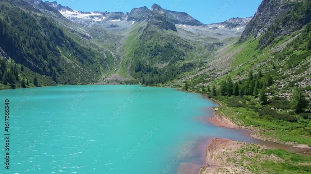 Stunning view of a mesmerizing emerald-blue lake nestled amidst towering green mountains, surrounded by dense forests and a clear sky. Stunning view of a mesmerizing emerald-blue lake nestled amidst towering green mountains, surrounded by dense forests and a clear sky.