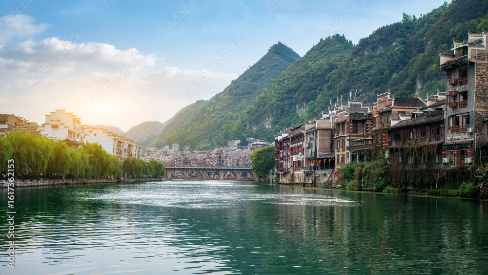 Fototapeta premium Picturesque Chinese Town by River with Mountains