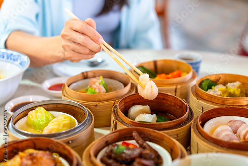 Young woman traveler eating traditional Chinese Dim Sum at restaurant