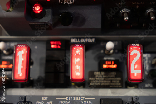 Close up of the engine and auxiliary power unit fire handles of a 737 commercial airplane. Fire handle lights are illuminated.