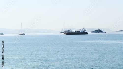 Wallpaper Mural Peaceful water landscape in Varkiza, Greece. Calm sea reflects clear sky, with several anchored boats and yachts on the horizon. Misty hills in background. No people Torontodigital.ca