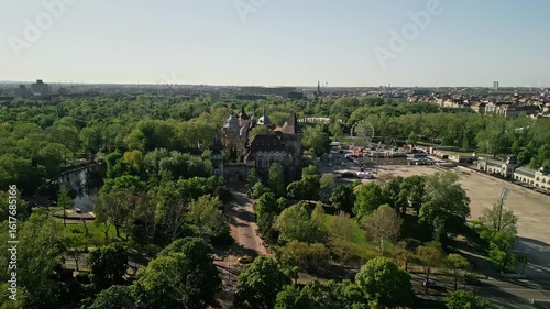 Morning drone video starting from ground at City Park lake, ascending to show Vajdahunyad Castle, the Museum of Ethnography, and Budapest’s Pest side skyline in soft morning light.  