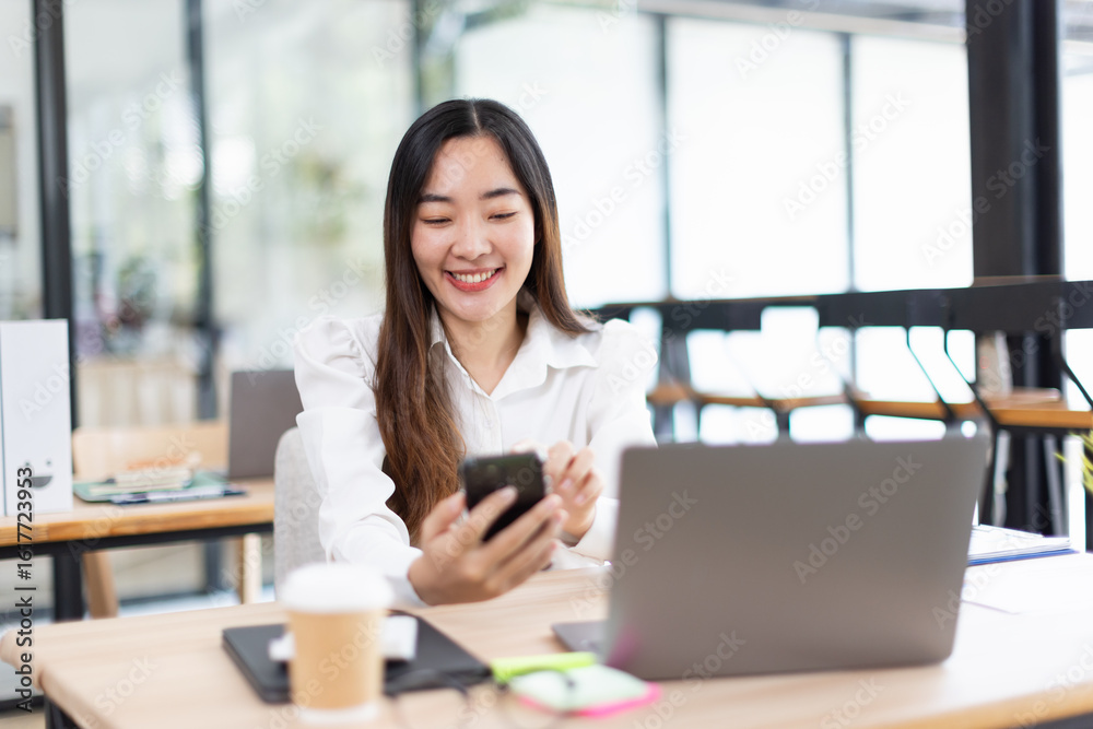 Fototapeta premium Asian woman talking on smartphone with laptop and project business planning in modern office.