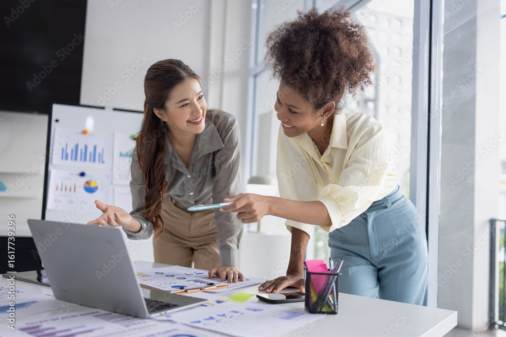 Fototapeta premium Two business woman working together for analysis data plan business strategies at desk in office, Business discussing and startup concept.