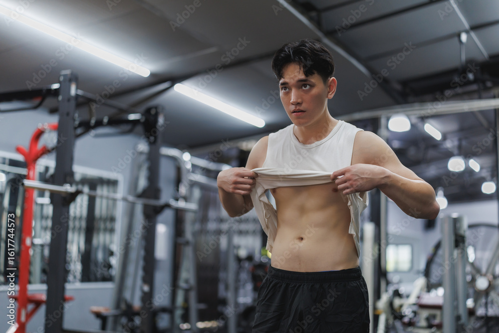 Fototapeta premium Young athlete showing abs in gym after workout