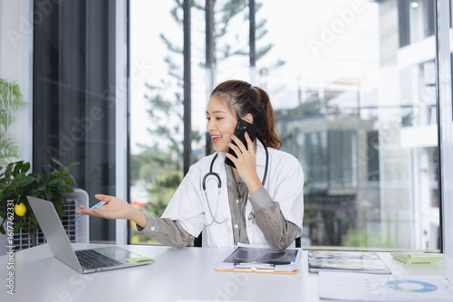 portrait of a confident female doctor using laptop sitting at working desk in hospital, Medical and health care concept.