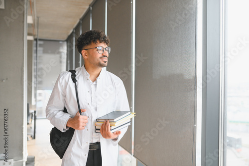 Foto Medical student walking in university hallway carrying books