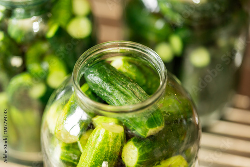 Canvas Print Glass jars filled with fresh cucumbers and spices, ready for traditional pickling on a rustic kitchen counter