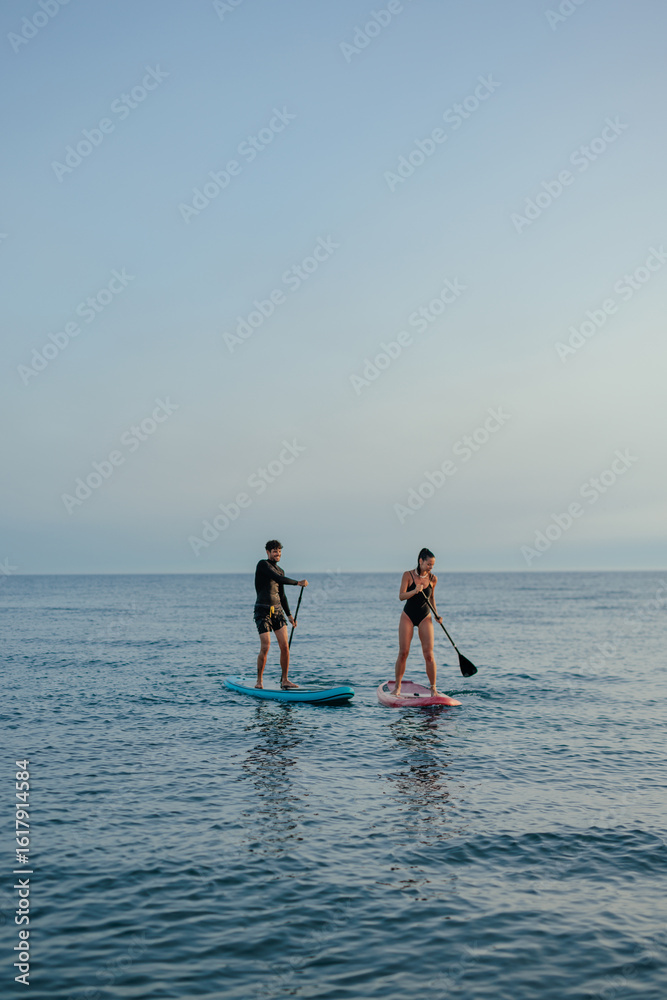 Naklejka premium Two people paddling on paddleboards