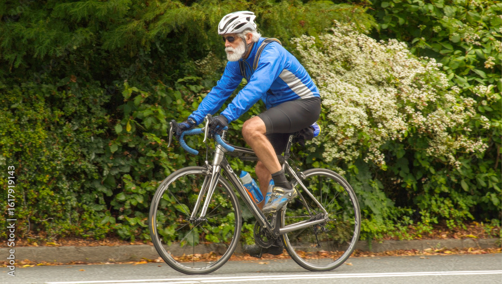 Fototapeta premium Inspiring image of a vibrant elderly man enjoying a bike ride, showcasing health and activity in golden years. Perfect for themes of active aging, well-being, and senior fitness