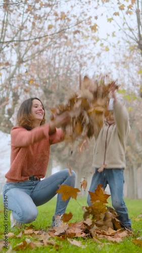 Mother and child joyfully playing in autumn leaves.