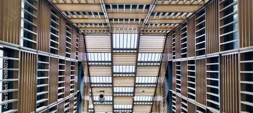 Canvastavla A striking low-angle, wide shot looking directly up into a modern building's atrium and large indoor space, showcasing an intricate ceiling and skylight design