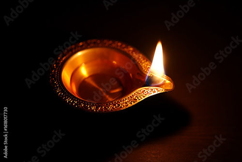Ornate brass oil lamp with bright flame diya light