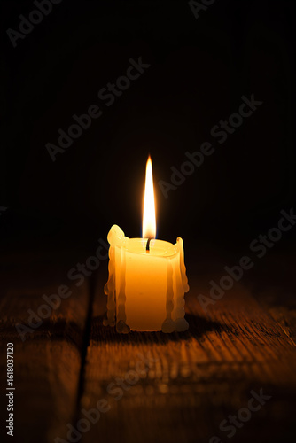 Glowing candle with dripping wax on wooden surface
