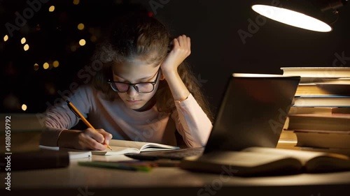 Girl studying late at night using laptop and taking notes
