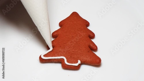 Gingerbread in the shape of a New Year tree cookies decorated and covered with liquid white sugar icing. Christmas Gingerbread cookies close-up during cooking