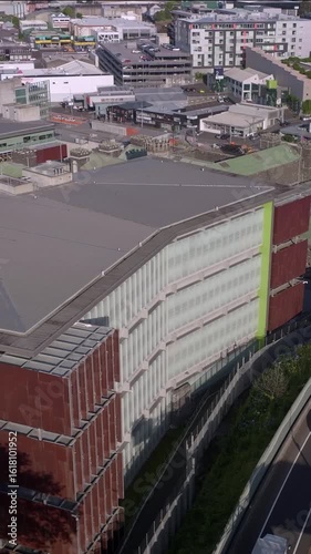 Aerial view of a Mt Eden Prison, with a unique design, located next to a highway in Auckland, New Zealand. The building's architecture stands out against the urban landscape.