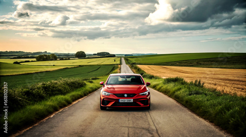 Red sports car driving on a paved country road