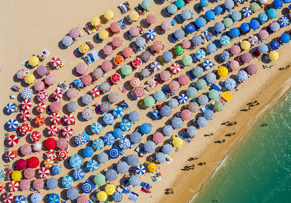 Fototapeta premium Vibrant summer escape awaits with a colorful aerial view of beach umbrellas and turquoise waters, perfect for travel brochures and vacation promotions
