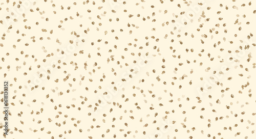 A close-up, high-angle view of a light tan textured background with a random scattering of small, dark brown, oval-shaped seeds, creating a natural and organic pattern