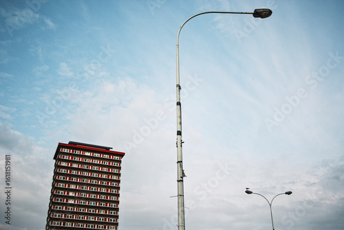 Low-angle view of streetlamps and residential tower against blue sky, expressing visual geometry, verticality and urban infrastructure in contemporary development zones.