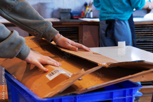 Obraz na plátně Student folding cardboard for reuse or recycling