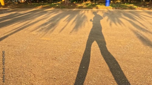 point of view of man shadow running or jogging on asphalt road in the afternoon