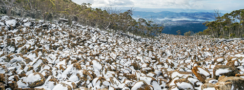 Panorama view of snow covering boulders in a rockfall in a mountain valley